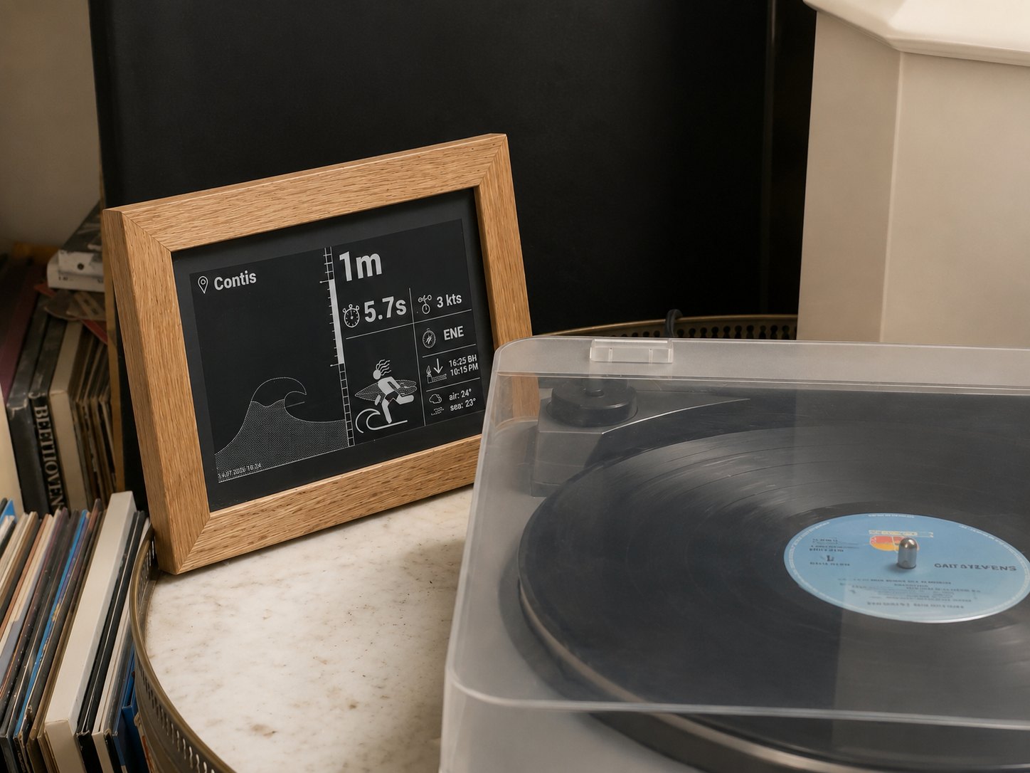 Un Wignet en cadre de chêne affichant la houle du spot de Contis, posé près d’une platine vinyle et d’une pile de disques.